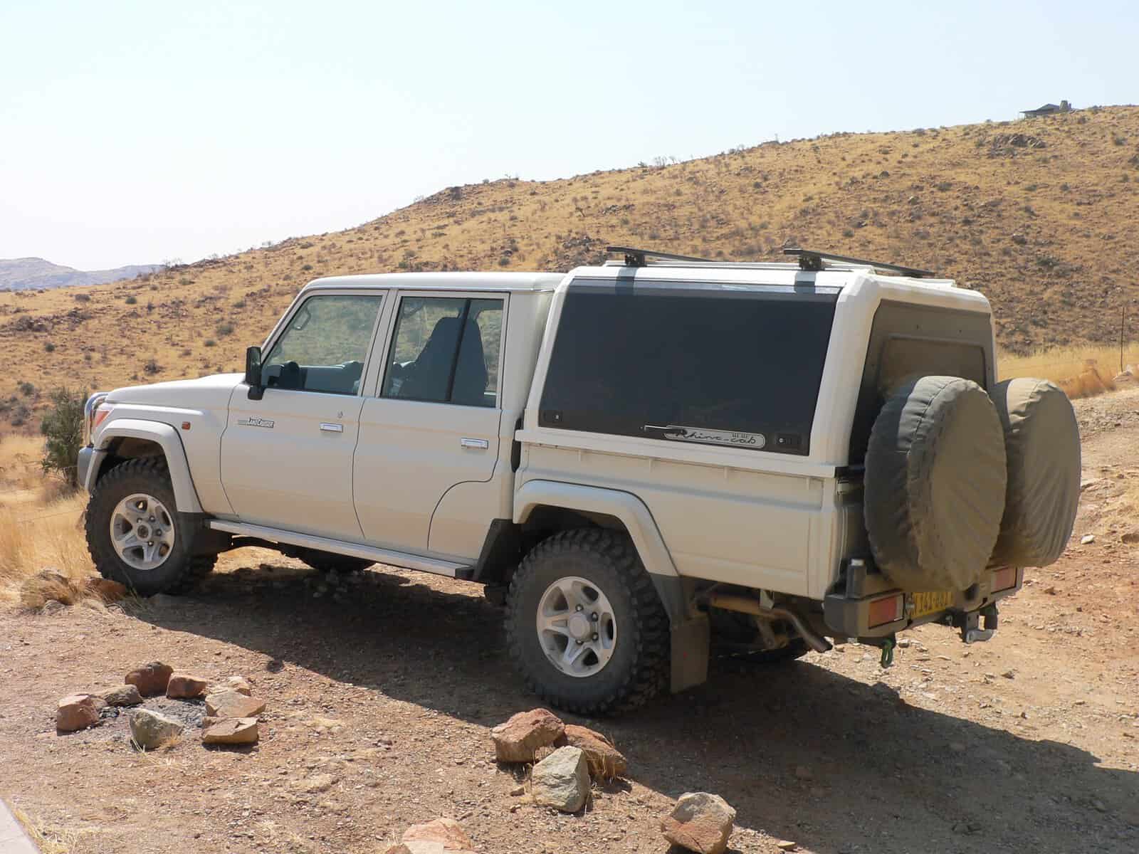 Weißer Landcruiser 4x4 Mietwagen in Namibia in der weiten Wüste Namibias in der Seitenansicht
